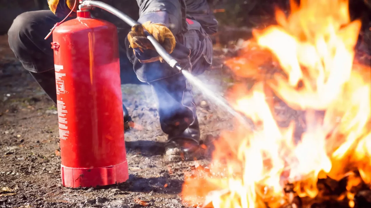 Fire extinguisher training. A close-up of a fire extinguisher and fire