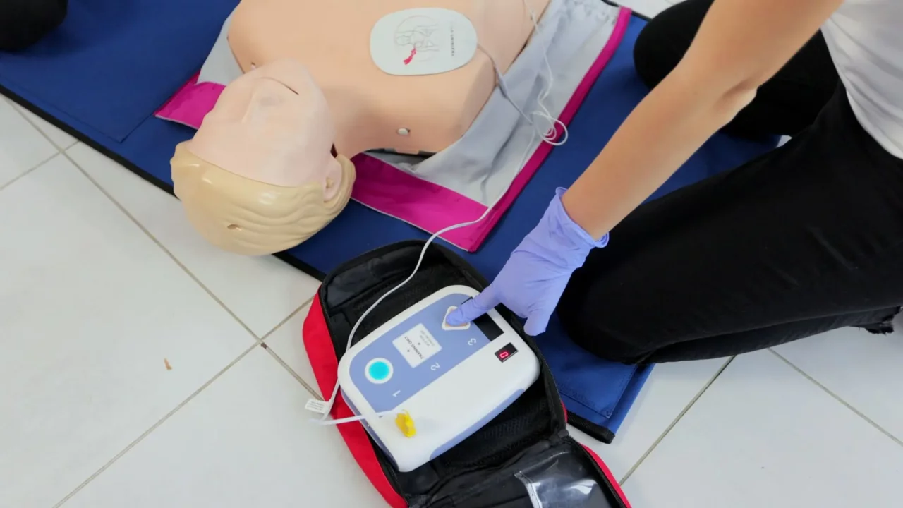 First aid training. A person trainign to use an AED device.