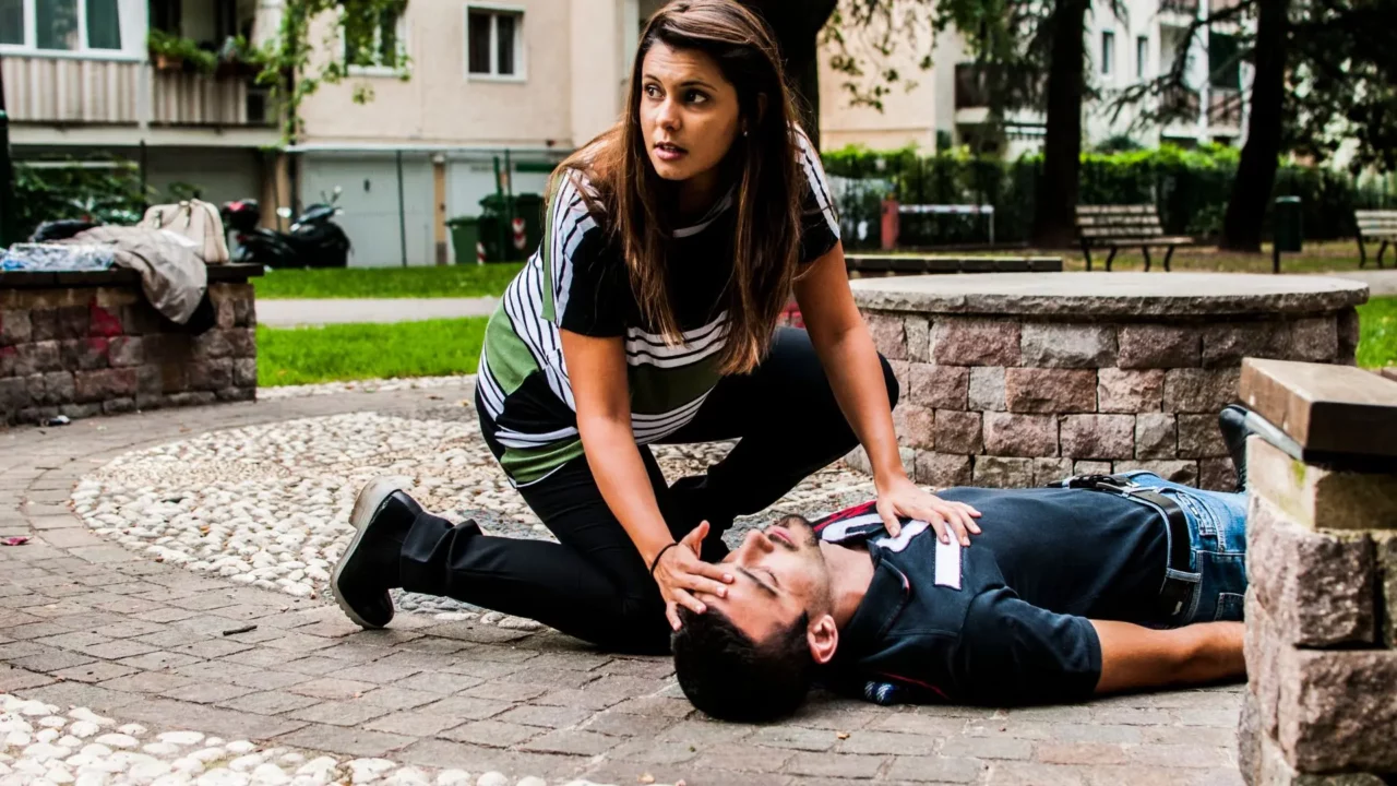No Panic Training. An emergency situation in a park. A woman is helping a man who has passed out.